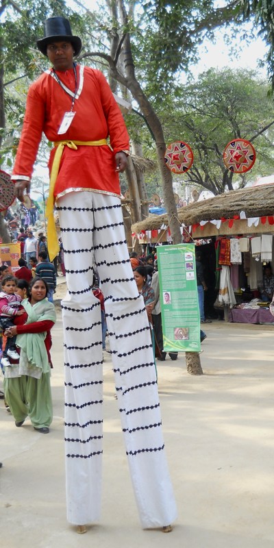 a walking performer standing on two bamboo poles
