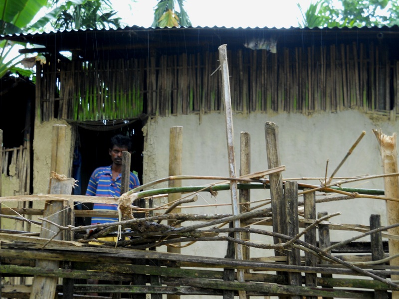 a tea tribesman-'kuli' in his bamboo made house with bamboo fencing